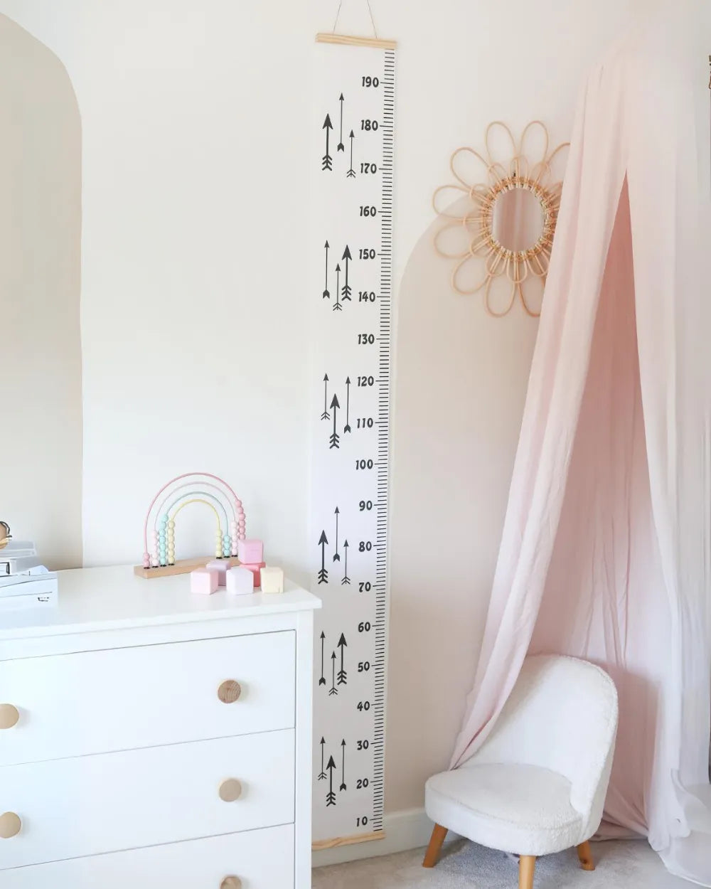 a child's room with a white dresser and pink curtains