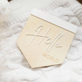 a close up of a wooden sign on a white blanket