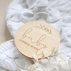 a wooden baby announcement on a white blanket