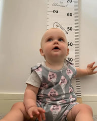 a baby sitting on the floor next to a ruler