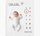 a baby laying on a blanket next to a clock