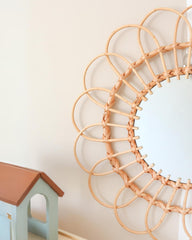 a round mirror hanging on a wall next to a toy house