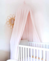 a white crib with a pink canopy over it