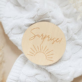 a wooden brooch with the words surprise written on it