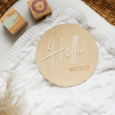a wooden name sign sitting on top of a white blanket