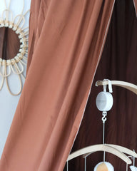 a baby crib with a brown curtain and a mirror