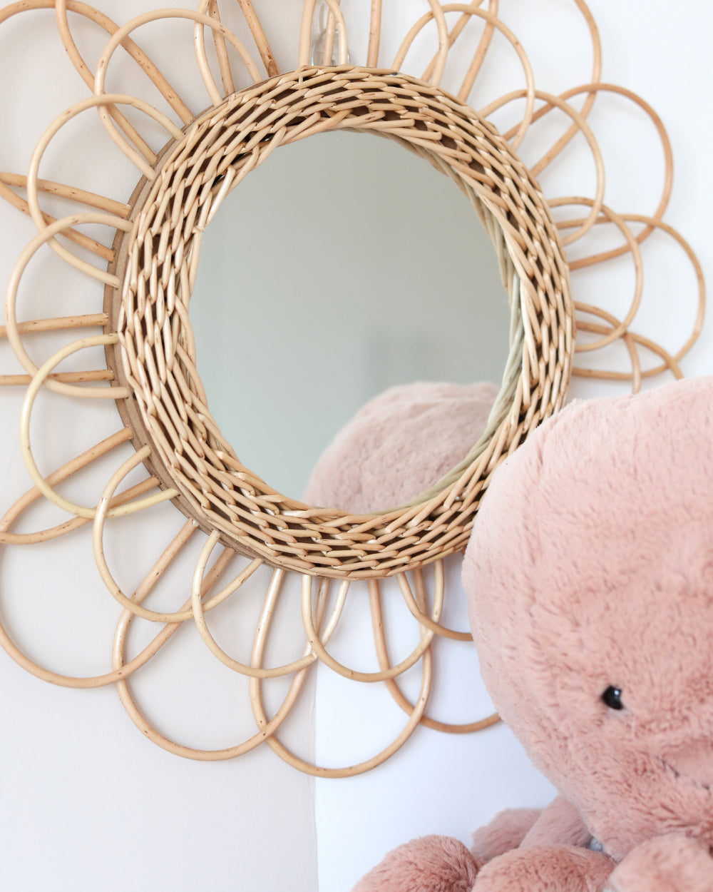 a pink teddy bear sitting in front of a mirror