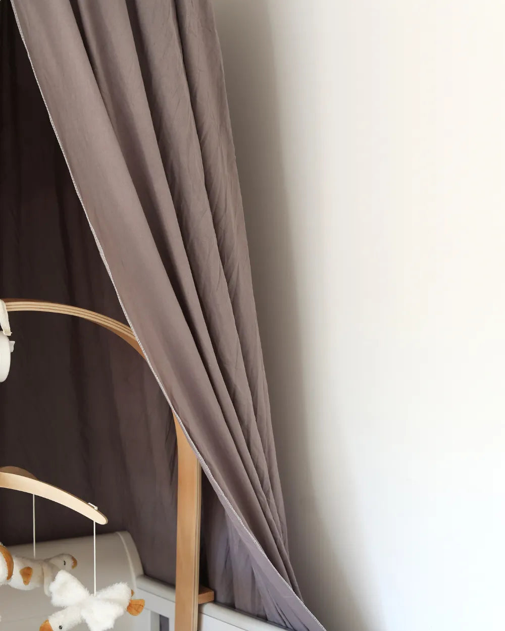 a baby crib with a teddy bear hanging from it's side