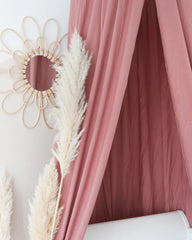 a bed with a pink canopy and a mirror on the wall