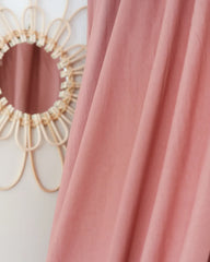 a pink curtain with a circular mirror on the wall